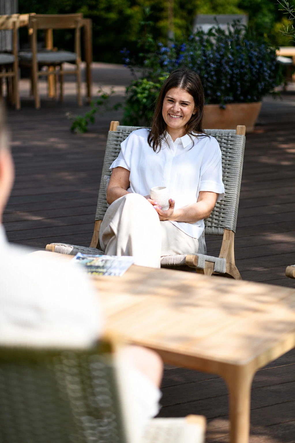 Ein Model sitzt im Lumera Loungesessel auf einer Terrasse